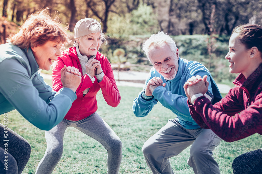 Fototapeta premium Retired people looking at couch and doing morning exercises
