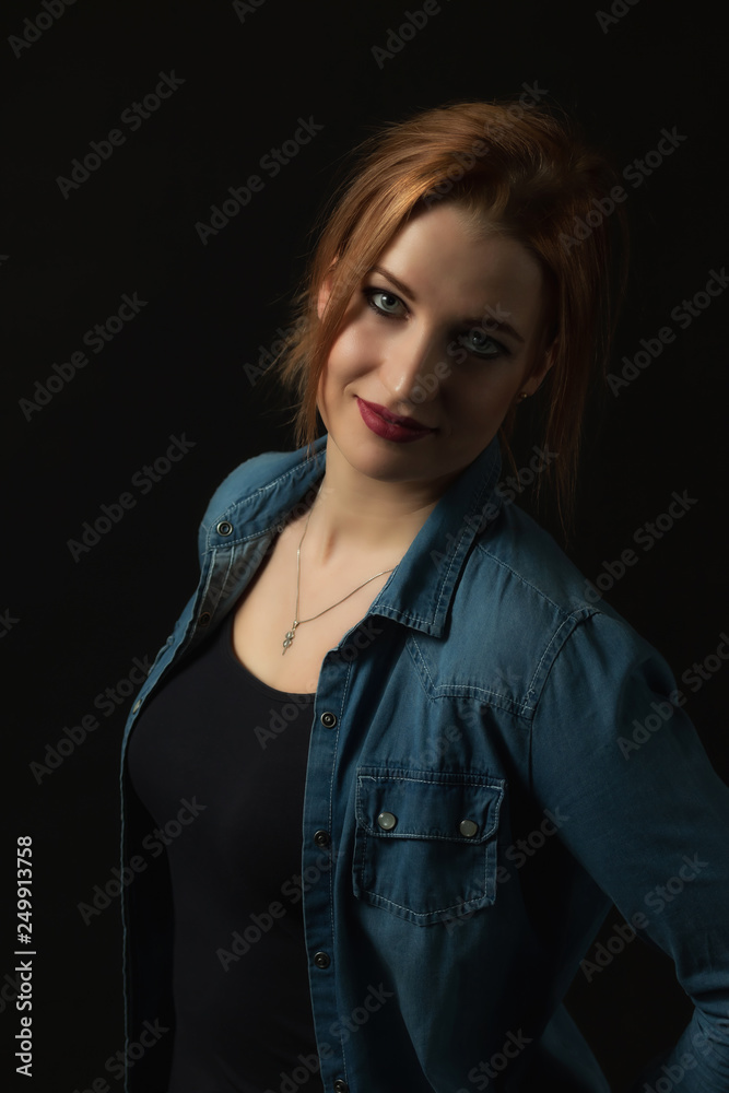 Low key portrait of posing young attractive woman on the black background. Vertically. 