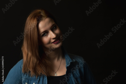 Low key portrait of smiling young attractive woman on the black background. 