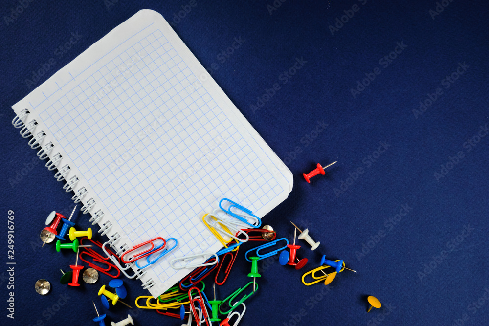 Fototapeta premium school notebook on a blue background, spiral notepad on a dack blue background with selected area and colorful clips