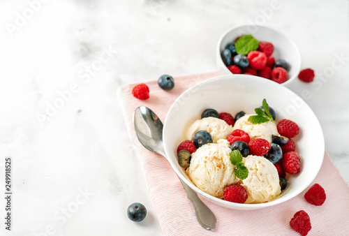 Close up of vanilla ice cream with berries on white table