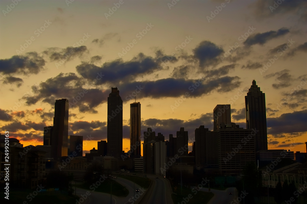 A dramatic silhouette of a cluster of buildings set against a golden sunset.