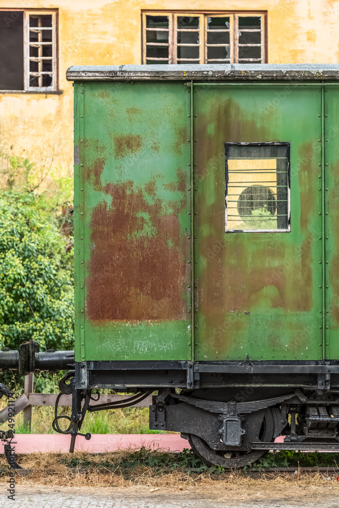 View of a abandoned and older rustic train wagon, yellow building as background View of a abandoned and older rustic train wagon, yellow building as background