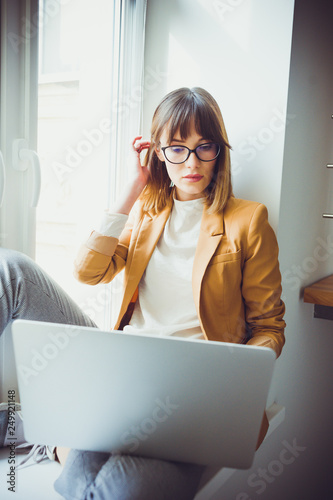 Beautiful young woman wearing casual in eyeglasses working by laptop in the office