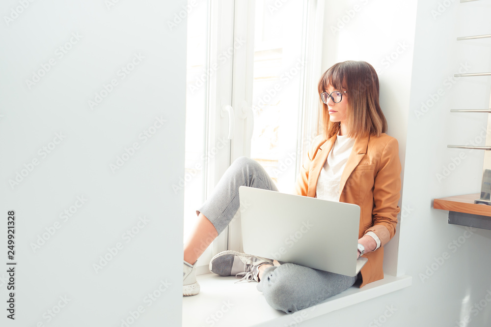 Beautiful young woman wearing casual in eyeglasses working by laptop in the office Beautiful young woman wearing casual in eyeglasses working by laptop in the office
