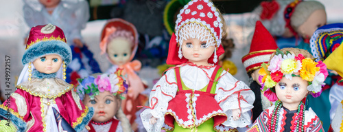 national dolls in beautiful dresses and handmade hats at the exhibition on the street. banner
