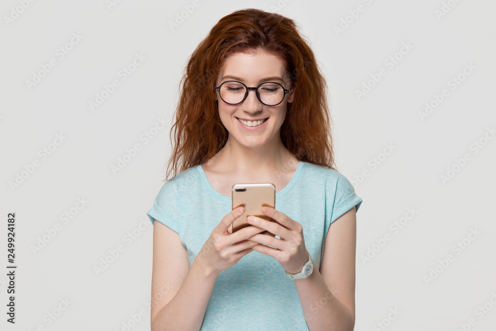 Happy young redhead woman in glasses holding mobile phone Happy young redhead woman in glasses holding mobile phone