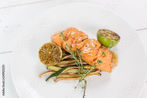 Salmon with lime and grilled vegetables witn sauce on white plate. Healthy food concept