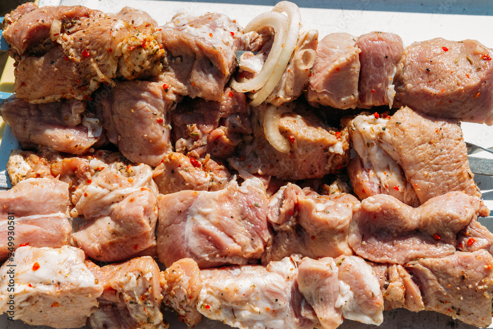 pieces of raw meat on skewers lies on a white tray. barbecue. cook meat with onions and peppers. pickled, picnic, street food pieces of raw meat on skewers lies on a white tray. barbecue. cook meat with onions and peppers. pickled, picnic, street food