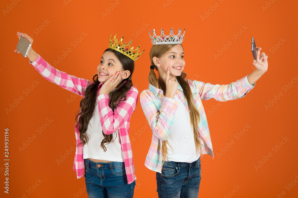 Egocentric princess. Kids wear golden crowns symbol princess. Warning signs of spoiled child. Avoid raising spoiled kids. Girls taking selfie photo smartphone camera. Spoiled children concept