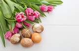 Easter background with bouquet of pink tulips and colorful eggs .