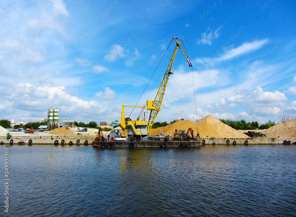 Crane on a barge on the water and sky background. River Moskow, Russia. 