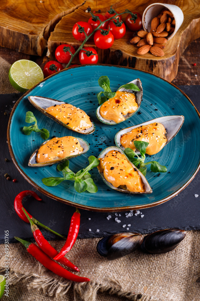Large blue mussels on a blue plate on a wooden background, near the rope and products Large blue mussels on a blue plate on a wooden background, near the rope and products