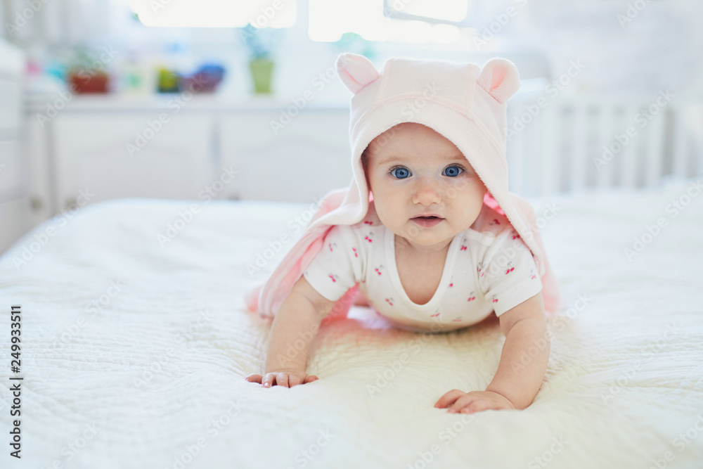 baby girl relaxing in bedroom in pink clothes or towel with ears baby girl relaxing in bedroom in pink clothes or towel with ears