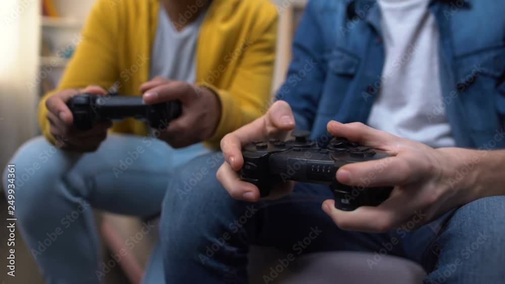 Multiracial friends playing computer games, closeup on hands with joysticks Multiracial friends playing computer games, closeup on hands with joysticks