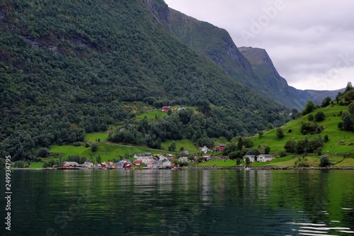 Holy grail illustrated from Sognefjord or Sognefjorden created from mountain range with blue sky and reflection in clear water and having a wooden dock point out in a river in Flåm