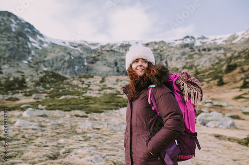 mountaineer girl with a backpack on her back looks around the high hills and the green meadows © NatRomero