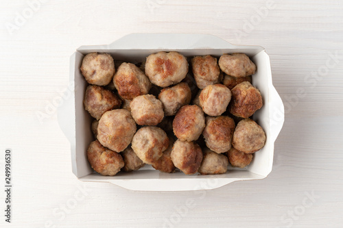 Grilled meatballs in paper lunchbox on wooden background