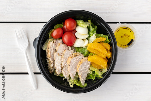 Healthy food to go in round lunch box on wooden background. flat lay..