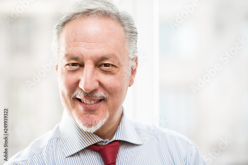 Bright portrait of a senior business man against a bright office background