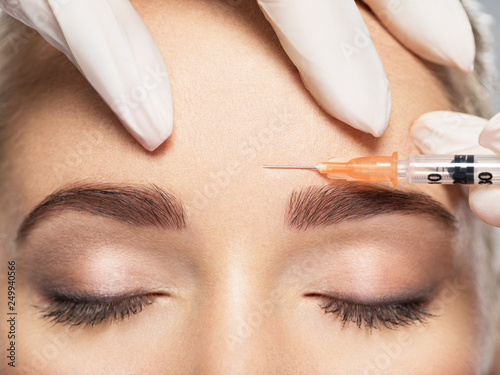 Woman getting cosmetic injection of botox near eyes photo