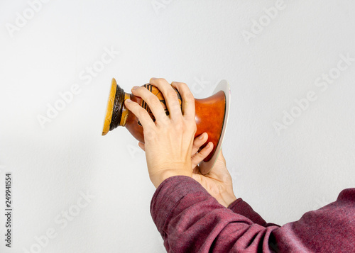 Hands tilting a gourd container (cuia) upside-down to form a mate wall, as part of the process of making the chimarrao, a Brazilian traditional drink, against white background, side view photo