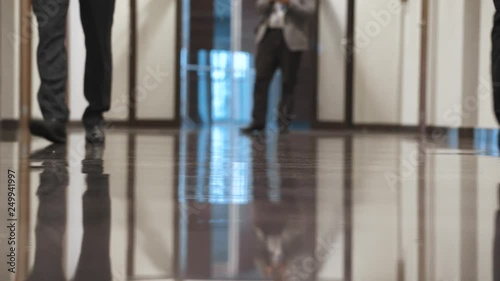 Men in business suits and shiny shoes go down the hall. photo