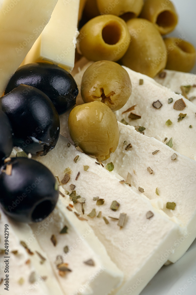 Exquisite festive snack closeup. Traditional Swiss, French, Italian, European delicacy for the holiday table, buffet, party. Olives, different types of cheese, nuts, spices on a plate.