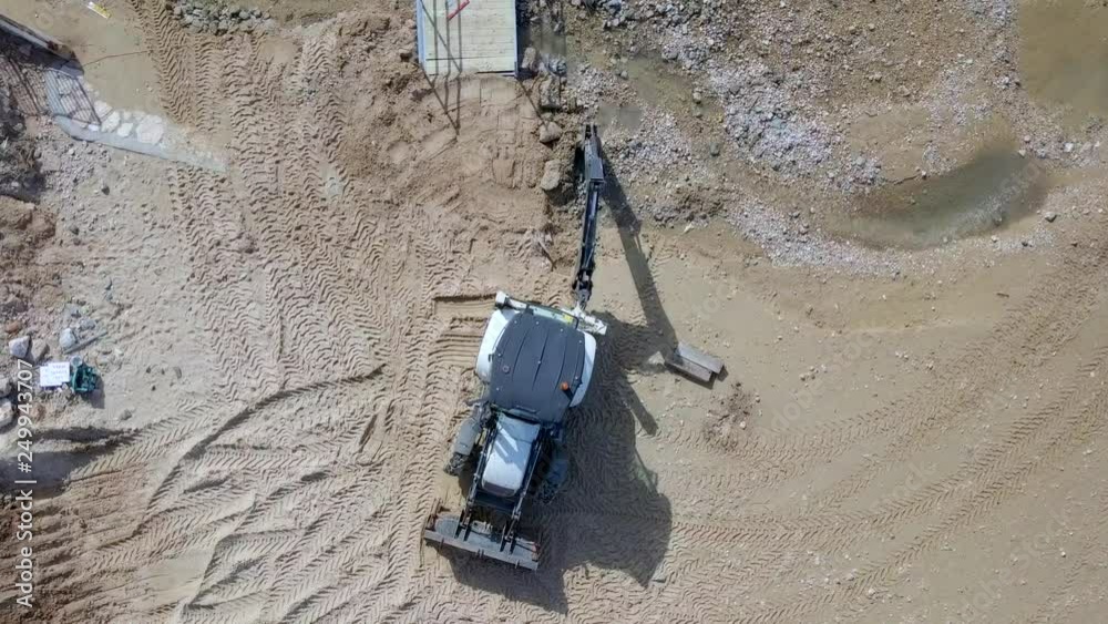 White tractor moving beach sand during the construction of a small bridge - Top down aerial footage. White tractor moving beach sand during the construction of a small bridge - Top down aerial footage.