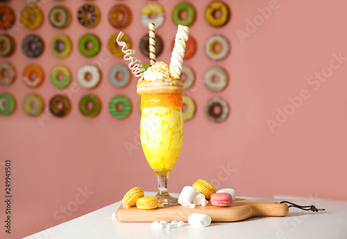 Tasty milk shake with sweets in glass and macarons served on table indoors