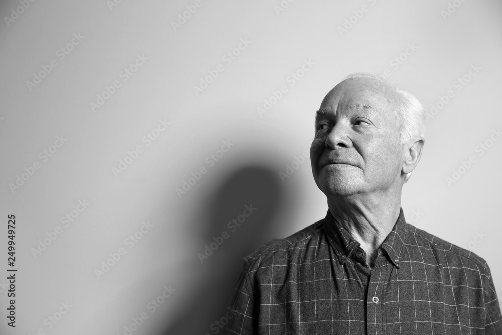Fototapeta premium Portrait of elderly man on light background, space for text. Black and white effect