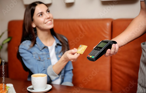 Woman using terminal for credit card payment in cafe