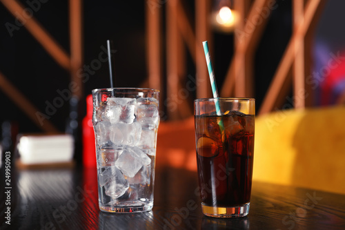 Glasses with refreshing cola and ice cubes on table indoors