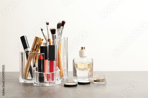 Lipstick holder with different makeup products on table against white background. Space for text
