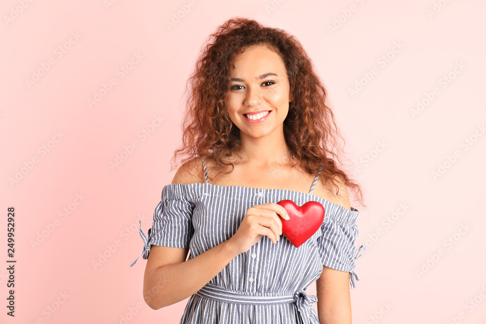 African-American woman holding wooden heart on color background African-American woman holding wooden heart on color background