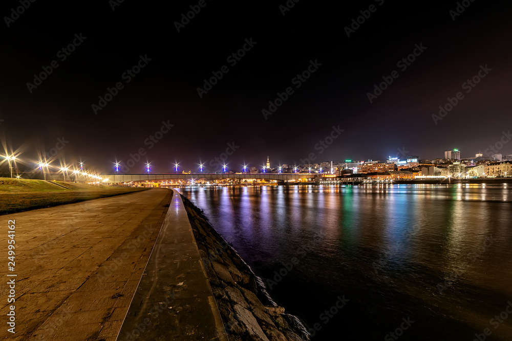 Belgrade, Serbia - February 10, 2019: A panorama of Belgrade seen from the banks of the Sava River by night with reflection. View of the Brankov Bridge. 