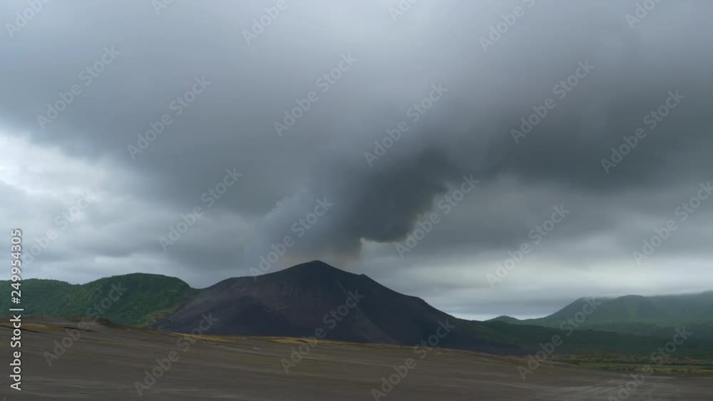 Thick dark grey smoke is coming out of the active volcano in Tanna, Vanuatu. Clouds of smoke gathering above the summits of a mountain range on a remote island in the Pacific. Shot of active volcano. Thick dark grey smoke is coming out of the active volcano in Tanna, Vanuatu. Clouds of smoke gathering above the summits of a mountain range on a remote island in the Pacific. Shot of active volcano.