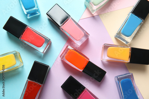 Bottles of nail polish on color background, top view photo