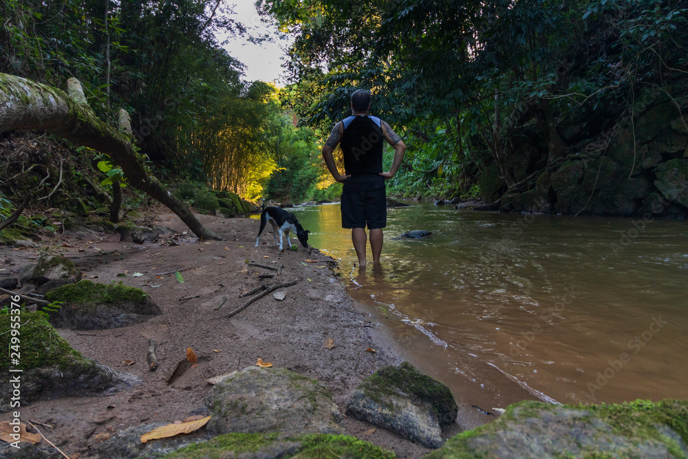 Man and dog relaxing and meditating beside a river in nature Man and dog relaxing and meditating beside a river in nature