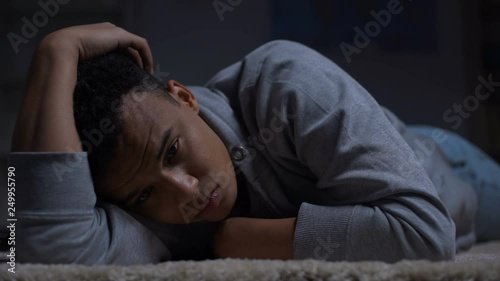 Depressed African-American teenager suffering loneliness in dark room, abuse