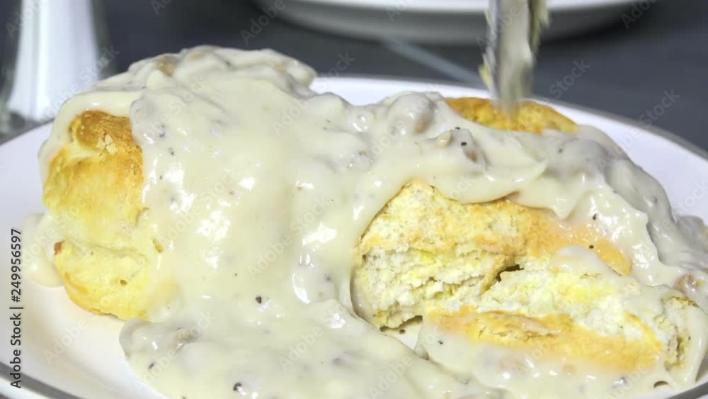 Spooning country gravy with sausage on biscuits slow motion