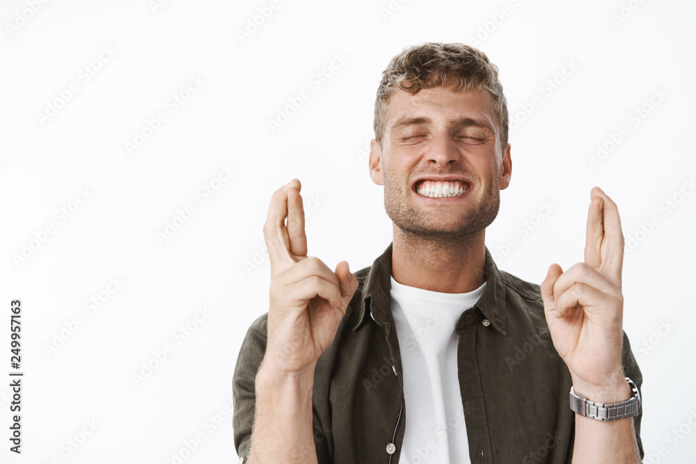 Excited and happy attractive fair-haired guy with bristle close eyes thrilled and smiling delighted as waiting for dream finally came true, cross fingers for good luck, praying hopefully Excited and happy attractive fair-haired guy with bristle close eyes thrilled and smiling delighted as waiting for dream finally came true, cross fingers for good luck, praying hopefully