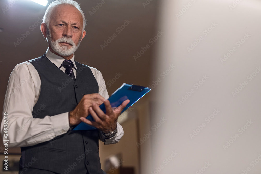 Portrait of confident mature businessman taking notes into clipboard. Portrait of confident mature businessman taking notes into clipboard.