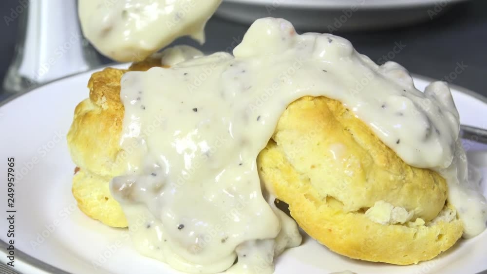 Spooning country gravy with sausage on biscuits slow motion