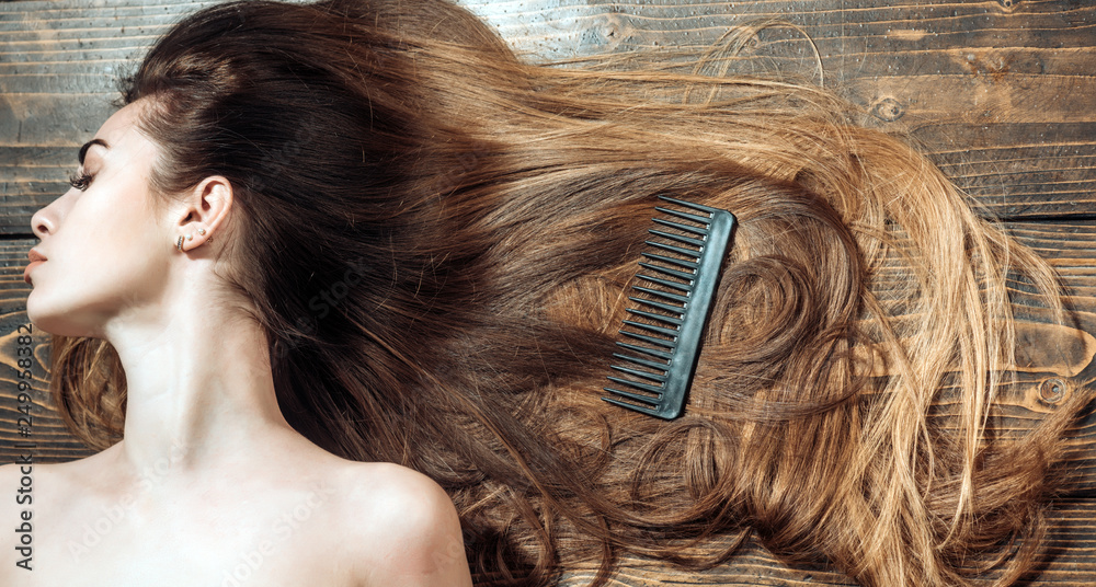 Fototapeta premium Woman with beautiful long hair on wooden background. Beautiful hair coloring woman. Long hair. Fashion haircut.