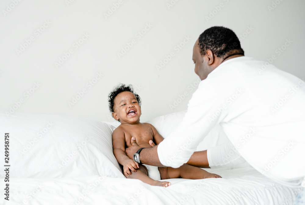 Fototapeta premium Dad playing with his baby on the bed