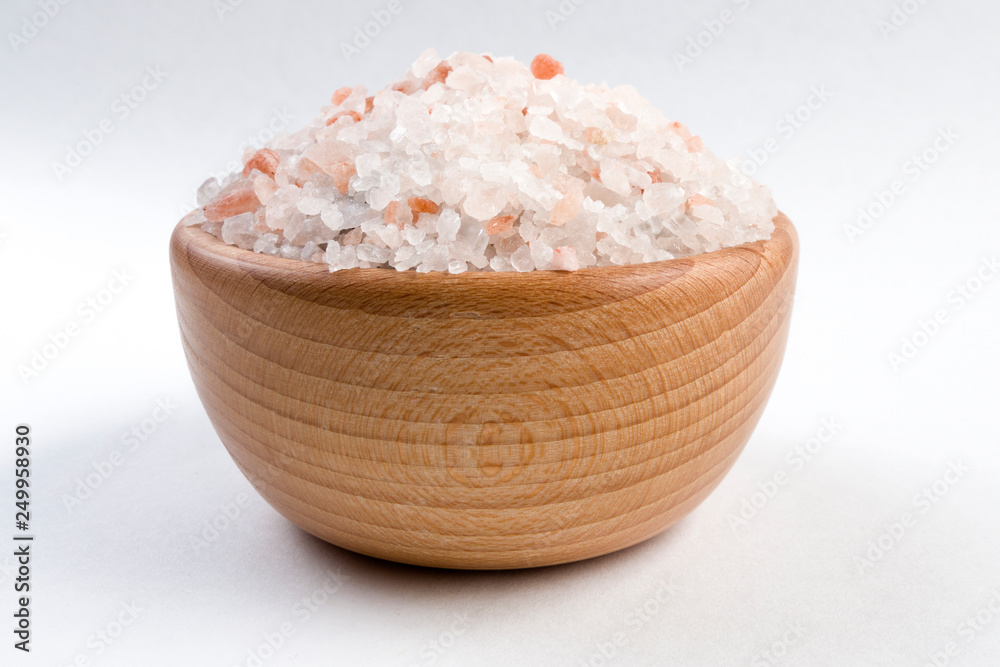 Himalayan pink salt  in wooden bowl isolated on white background.
