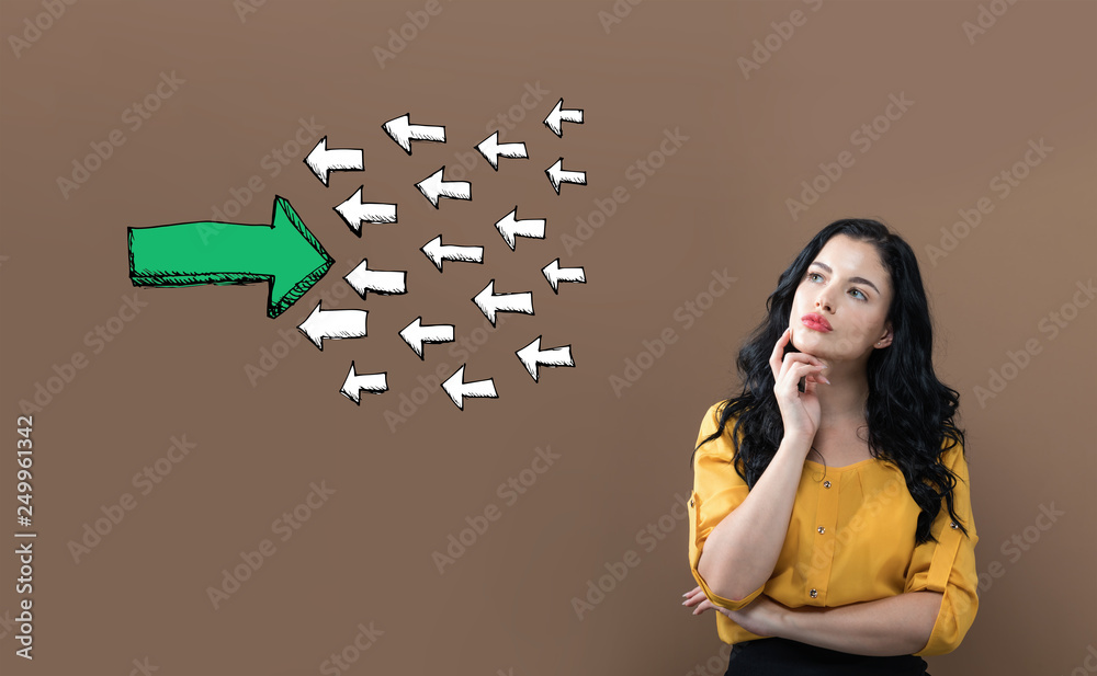Arrow facing in a opposite direction with young businesswoman on a brown background - obrazy, fototapety, plakaty 