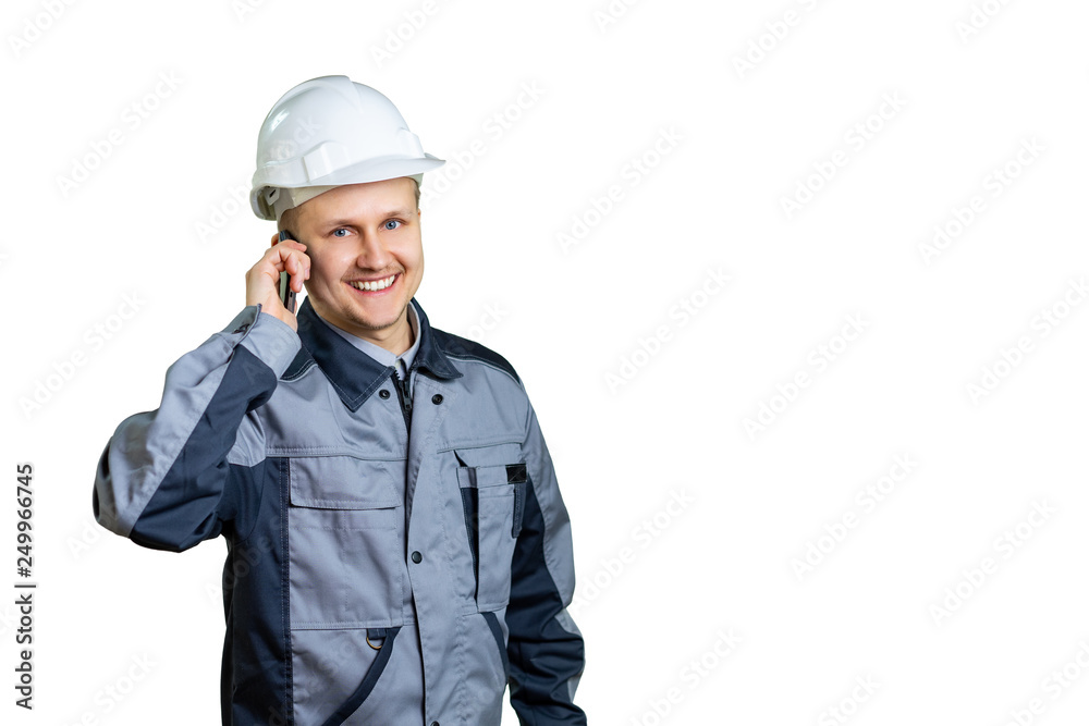 Handsome young builder engineer in overall talking on mobile phone isolated on a white background. Handsome young builder engineer in overall talking on mobile phone isolated on a white background.