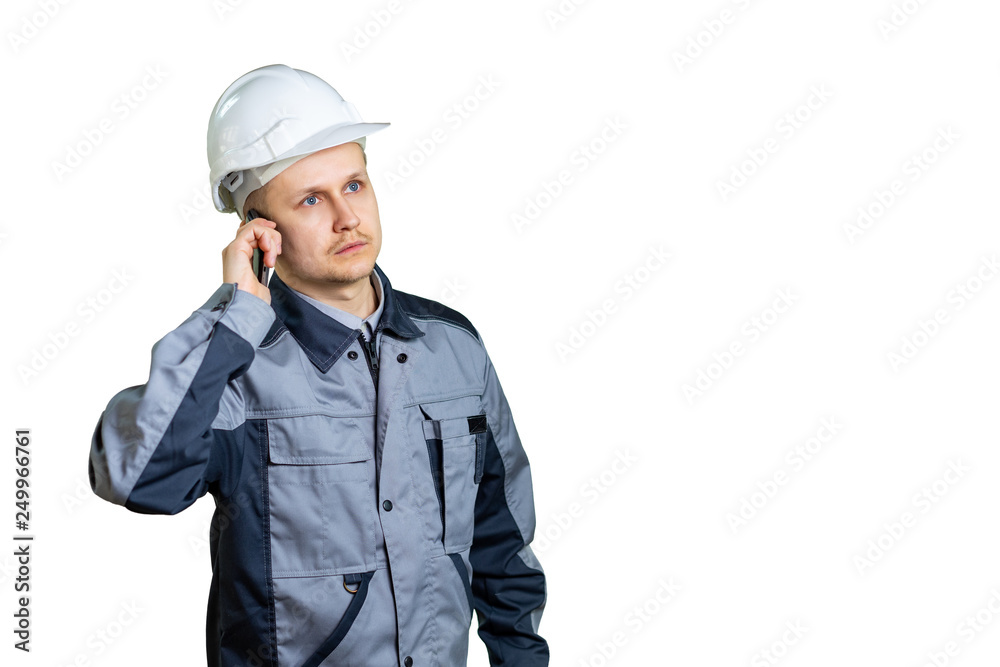 An engineer in a white helmet talking on the phone on a white background. He listens to the boss or new tasks for the repair of construction. isolated An engineer in a white helmet talking on the phone on a white background. He listens to the boss or new tasks for the repair of construction. isolated